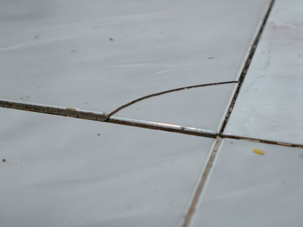 Cracks forming in a basement floor caused by foundation movement and settling in a West Virginia home.