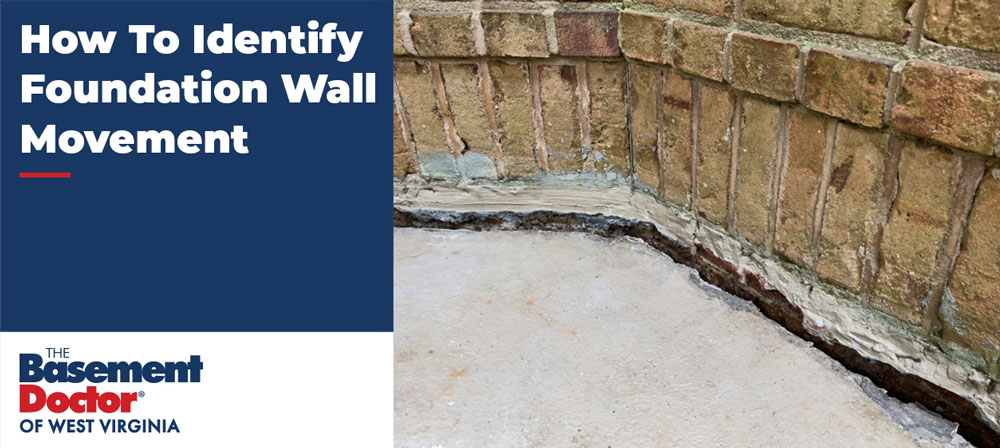 Horizontal crack along the bottom of a brick foundation wall where the wall meets the concrete floor, indicating foundation wall movement.